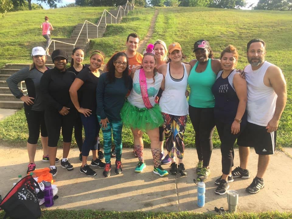 Group of diverse fitness enthusiasts posing together outdoors in a park after a workout session
