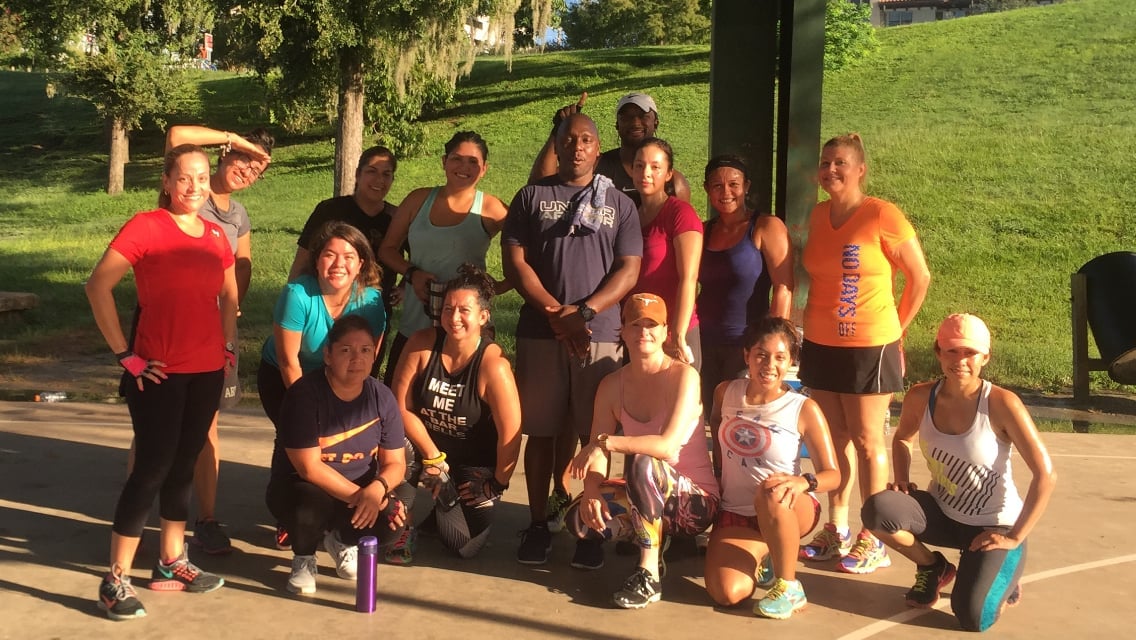 Group of diverse runners posing together outdoors on a sunny day at a park