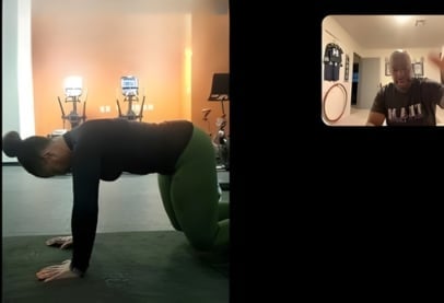 Person doing a plank exercise on a green mat during a video call workout session