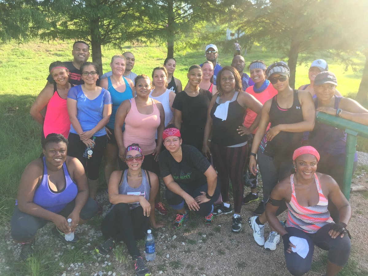 Large group of women in athletic wear posing together outdoors in a park