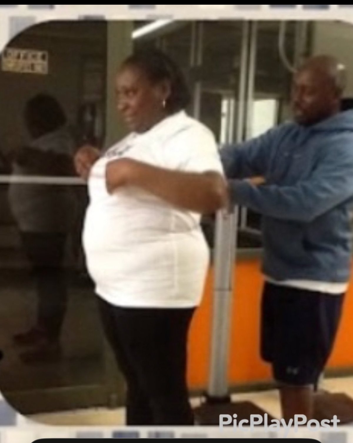 Two people standing inside a subway car, one wearing a white shirt and the other in a blue jacket, holding onto a metal pole