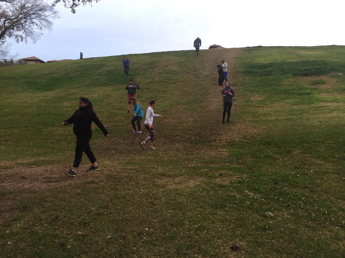 Group of people hiking on a green rolling hillside on an overcast day